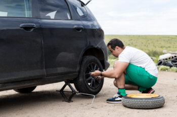 man fixing a car with a flat tire